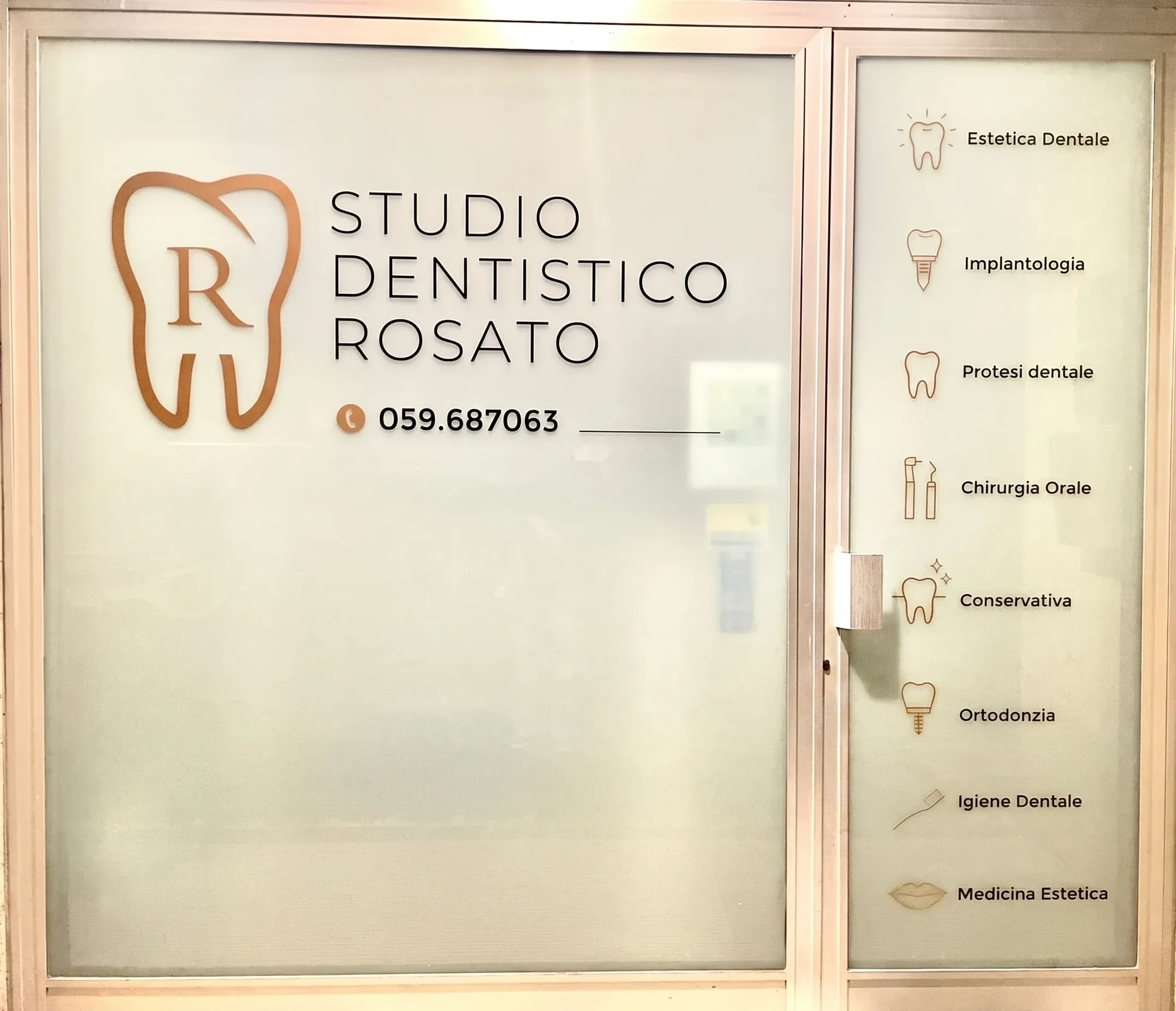 Vetrina dello Studio Dentistico Rosato in via Firenze a Carpi, con il logo e l'elenco dei trattamenti